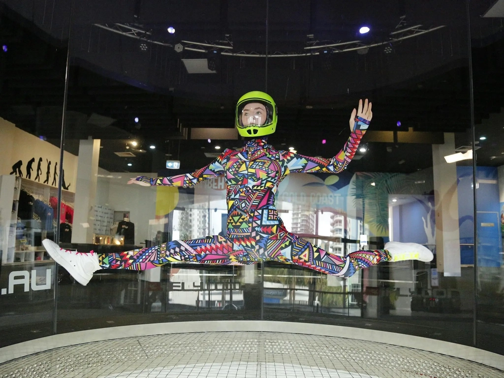 Freestyle flying by experienced junior flyer in colourful suit, performing the splits mid-air.