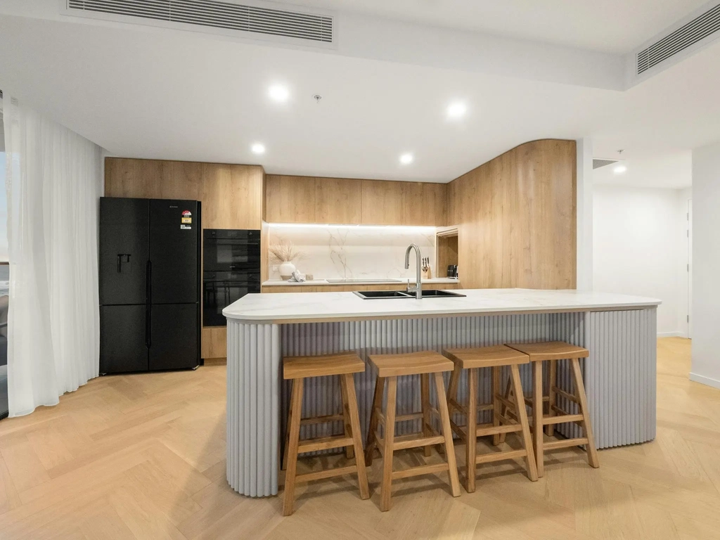 Kitchen with timber island, stone benchtop, stools and full-height oak joinery
