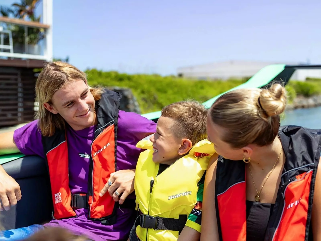 2 teens and 1 child sitting in their life jackets sitting on Arro Jet Boat.