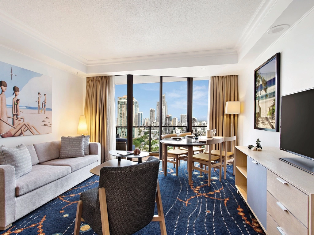 Suite with sofa, four piece dinette table with glassware and utensils, balcony, television