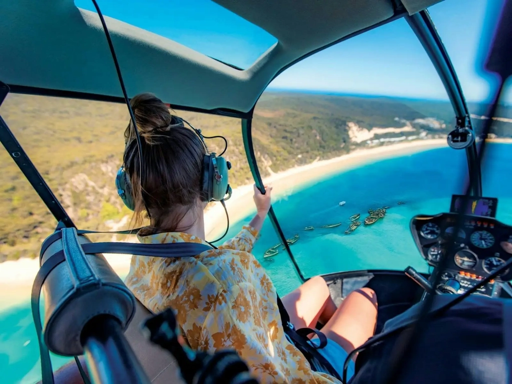 Women in a helicopter looking out over the view of the Tangalooma Wrecks and turquoise water