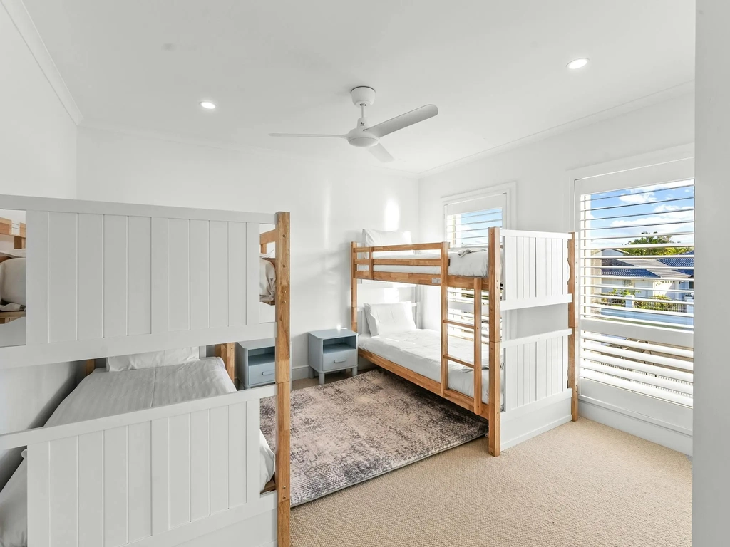 Bunk room with four single beds and coastal styling