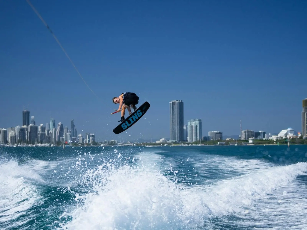 Wake boarder doing massive air grab of the board.