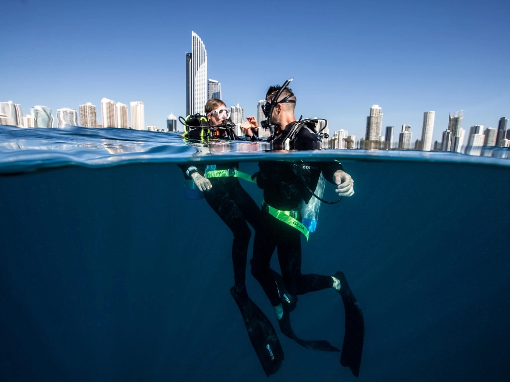 two scuba divers with the Gold Coast city building skyline behind them