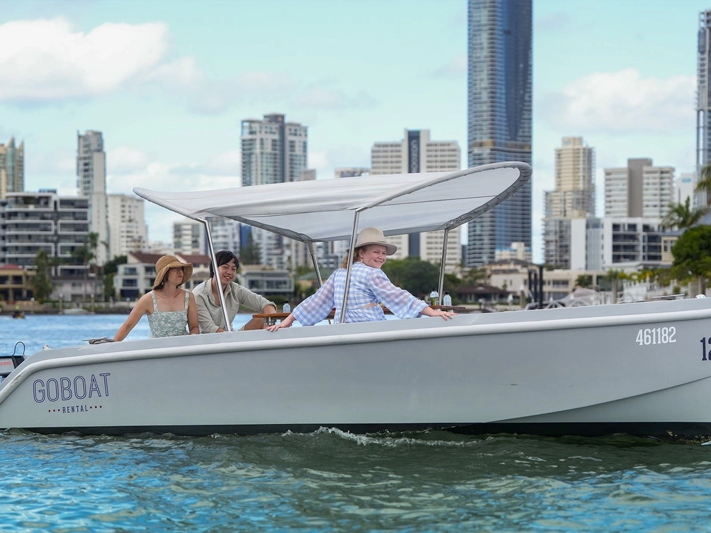 Three people smile from a GoBoat on the Nerang River