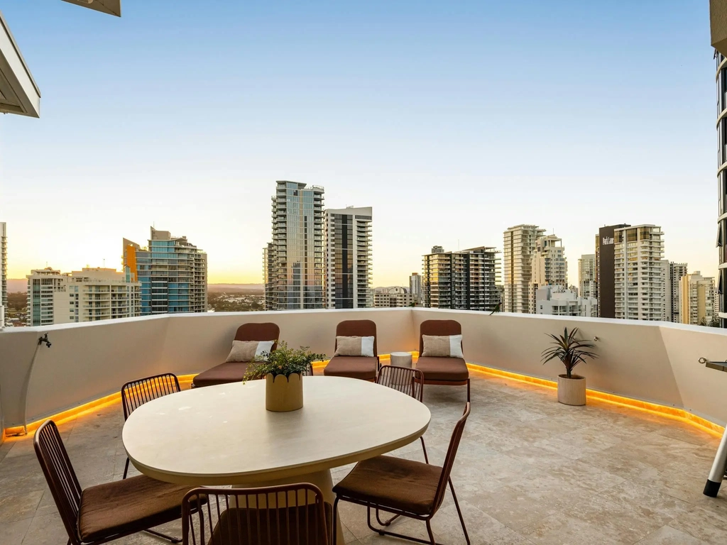 Rooftop terrace with an outdoor dining table, loungers and a barbecue at dusk
