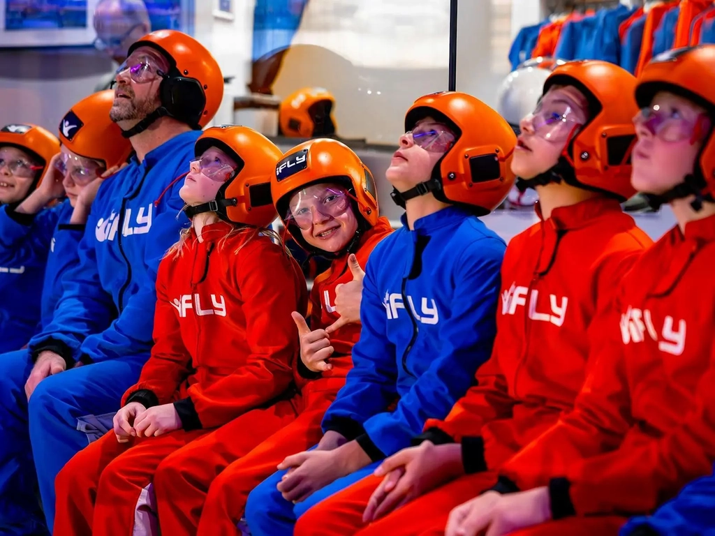 Kids and families in suits watching others fly while awaiting their turn.