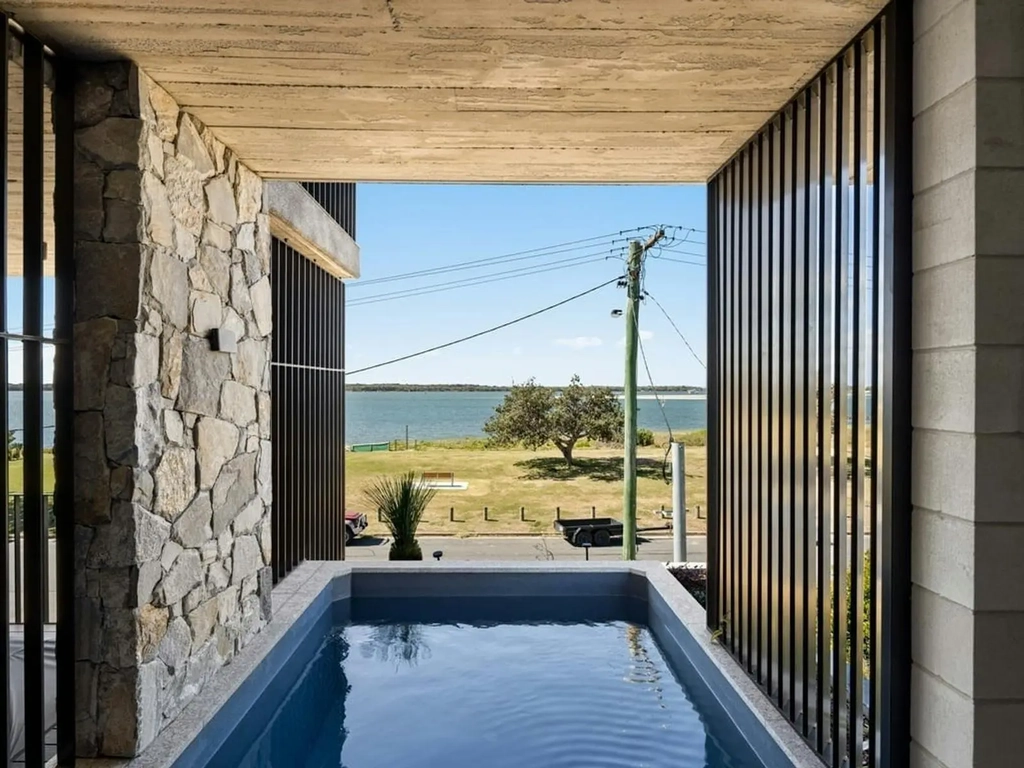 Outdoor spa set between a stone wall and timber screens facing the Broadwater