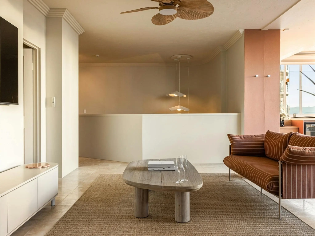 Upstairs lounge with a striped sofa, timber coffee table and wall television