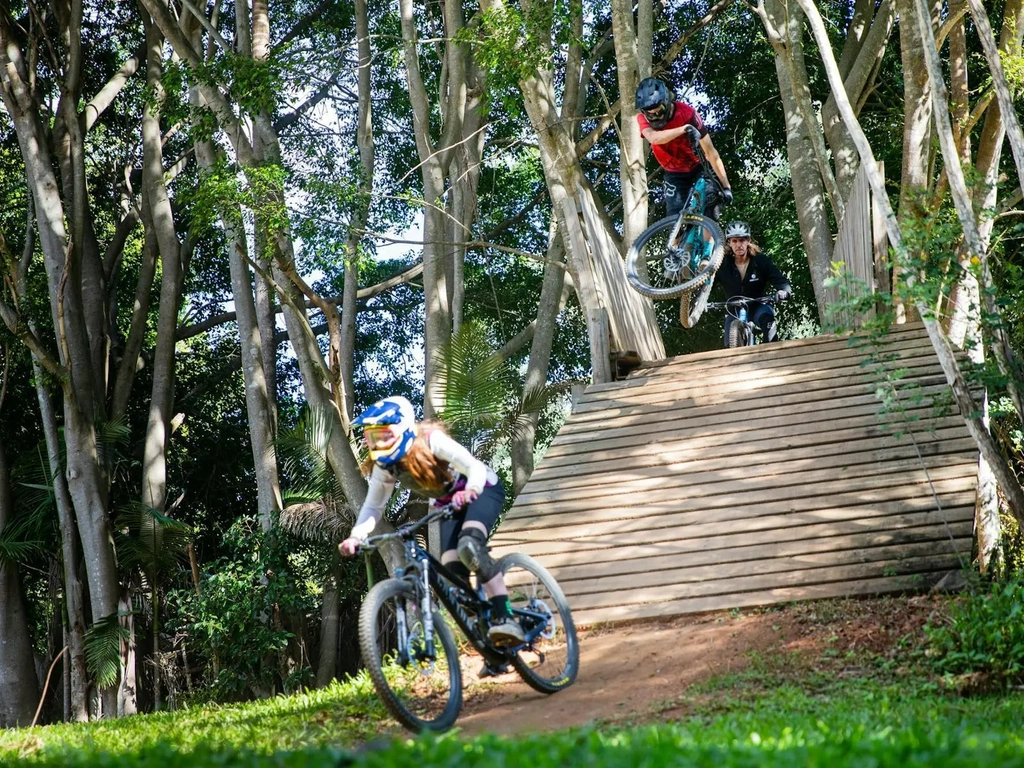 riders on trail performing tricks off a bridge