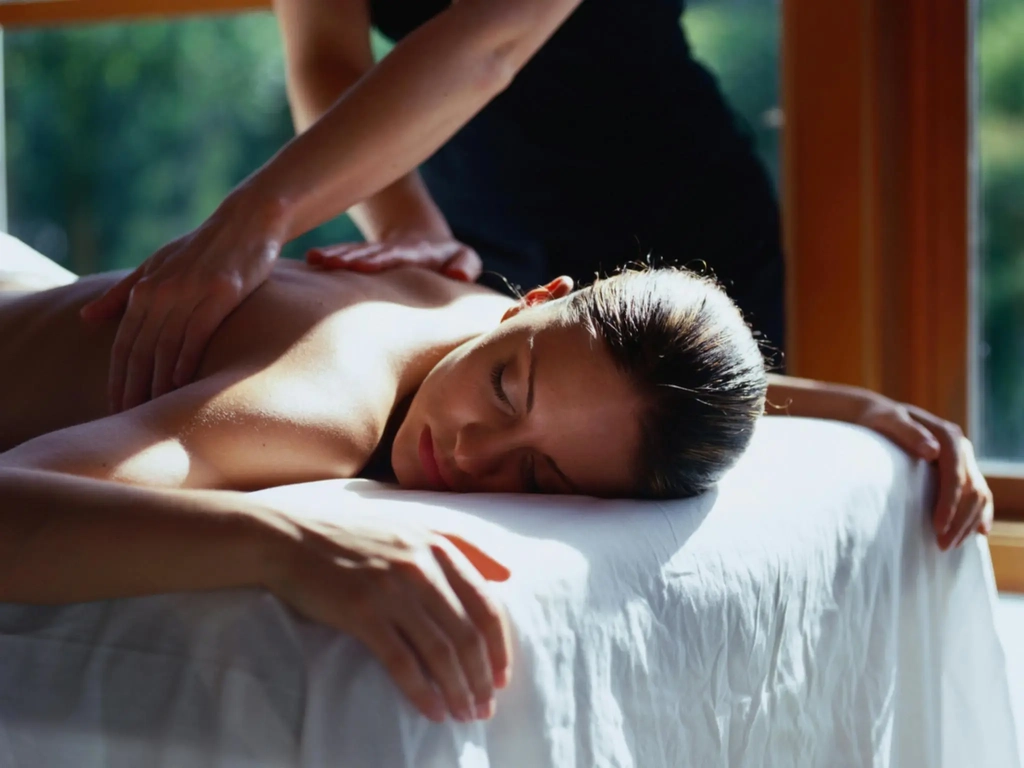 Woman having a massage as part of a couple lying on massage table with massage therapist