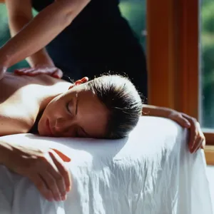 Woman having a massage as part of a couple lying on massage table with massage therapist